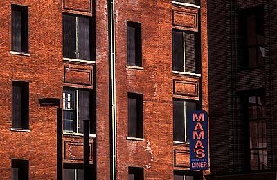 Neon restaurant sign, "Mama's Daughter's Restaurant", against red brick buildings. Location: TX, Dallas County, Dallas, Downtown. [ref. to #208.019]