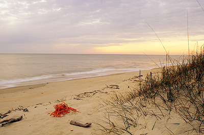 View west from beach dune in front of Captain Charlies Station, during a storm-obscured sunset. Location: NC, Brunswick County, Cape Fear Area, Bald Head Island, South Beach. [ref. to #233.128]