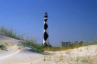 The lighthouse, with lightkeeper's cottage. Viewed over ocean-side dunes. Location: NC, Carteret County, Cape Lookout Nat. Seashore, Cape Lookout, Cape Lookout Lighthouse. [ref. to #233.494]