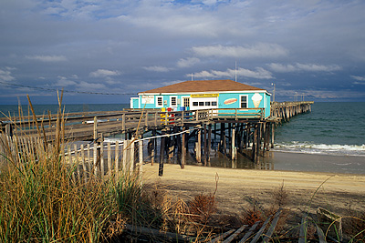 NC: Dare County, The Outer Banks, Nags Head & Kitty Hawk, on Bodie Island, Town of Nags Head, Outer Banks Fishing Pier, viewed across dunes; storm clouds in bkgd [Ask for #233.B53.]