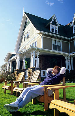 PE: Queens County, Anne's Land Area, Prince Edward Island National Park, The Delvay-by-the-Sea Hotel. Front view; woman relaxing on a lawn chair. MR. [Ask for #240.052.]