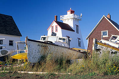 PE: Queens County, Anne's Land Area, North Rustico Harbor, North Rustico Lighthouse. Front view, with an abandoned beached fishing boat in frgd. [Ask for #240.103.]