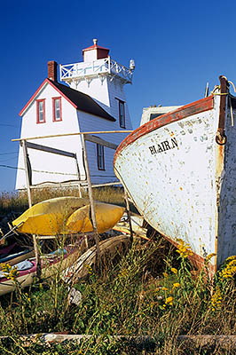 PE: Queens County, Anne's Land Area, North Rustico Harbor, North Rustico Lighthouse. Front view, with an abandoned beached fishing boat in frgd. [Ask for #240.104.]