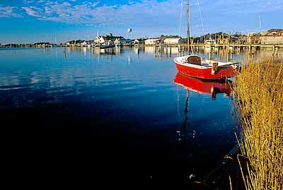 NC: Hyde County, The Outer Banks, Ocracoke Island, Ocracoke Village, View across harbor on Pamlico Sound (known as Silver Lake) towards village; red rowboat by dock [Ask for #241.330.]