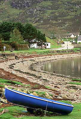 View across Loch Ewe towards village; village reflected in water; beached fishing boat in frgd. Location: UK, Scotland, Highlands Region, Ross & Cromarty District, Wester Ross, Poolewe. [ref. to #243.588]