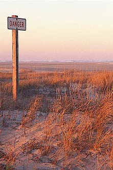 NC: Dare County, Hatteras National Seashore, Oregon Inlet, "DANGER" sign on dunes; rough ocean in bkgd; sunset light. [Ask for #249.103.]