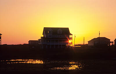 NC: Dare County, The Outer Banks, Hatteras Island, Rodanthe, Sun rising behind stilt vacation homes [Ask for #249.113.]