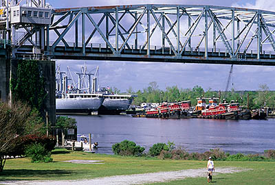 NC: New Hanover County, Cape Fear River Area, Wilmington, Wilmington Historic District, Riverside Park; view over Cape Fear River, towards the sea port, with red tugs at dock, viewed beneath the Cape Fear Bridge [Ask for #249.357.]