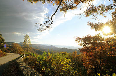 Autumn view of the parkway skirting out over a cliff, as the sun goes down behind it. Location: VA, Augusta County, The Blue Ridge Parkway, Humpback Mountain Area, Greenstone Overlook (MP 9). [ref. to #251.072]