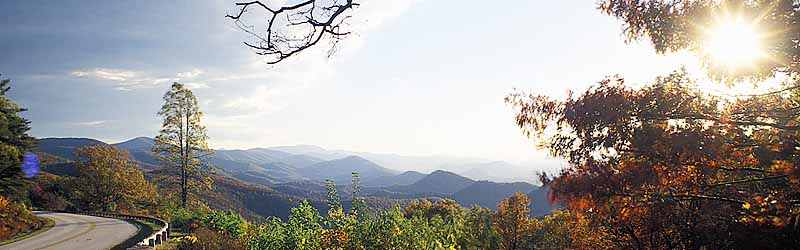 Autumn view of the parkway skirting out over a cliff, as the sun goes down behind it. Location: VA, Augusta County, The Blue Ridge Parkway, Humpback Mountain Area, Greenstone Overlook (MP 9). [ref. to #251.072]