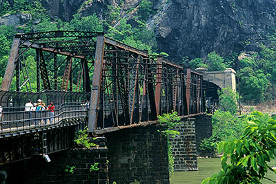 WV: Jefferson County, Potomac River Area, Harpers Ferry Nat. Hist. Park, Old Town, The Appalachian Trail crossing the Potomac River on a railroad trestle; Maryland Cliffs form a backdrop, and a railroad tunnel is visible [Ask for #251.291.]