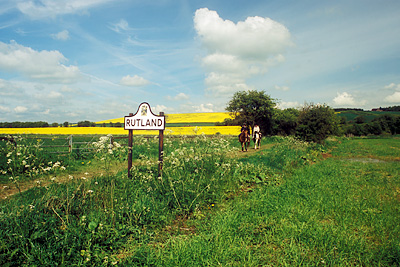 ENG: East Midlands Region, Rutland, River Welland Valley, Barrowden, Turtle Bridge, A traditional cast-iron county sign, freshly painted, sits by an abandoned road (now a foot path); horses and riders on the path. NR [Ask for #256.292.]