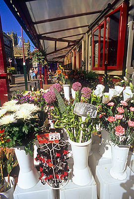 ENG: Manchester-Liverpool Urban Area, Blackpool Borough, Historic Town Center, Flower shop by a sidewalk cafe on Coronation Street offering cut flowers and gully doll key chains. [WARNING! Potentially offensive content.] [Ask for #262.051.]