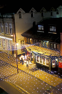 ENG: Manchester-Liverpool Urban Area, Blackpool Borough, Historic Town Center, People stand in front of a pub, Scruffy Murphys; Coronation St decorated in chandelier style lights as part of the Illuminations Festival, lighted and at night [Ask for #262.076.]