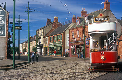 ENG: Northumbria Region, Durham, Beamish, The North of England Open Air Museum, The Town, Antique red double decker street car waits at a tram stop in front of a range of restored late 19th and early 20th c. commercial buildings [Ask for #262.299.]