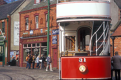 ENG: Northumbria Region, Durham, Beamish, The North of England Open Air Museum, The Town, Antique red double decker street car waits at a tram stop in front of a range of restored late 19th and early 20th c. commercial buildings [Ask for #262.300.]