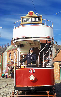 ENG: Northumbria Region, Durham, Beamish, The North of England Open Air Museum, The Town, Conductor in period costume drives an antique red double decker street car waits at a tram stop in front of a range of restored High Street [Ask for #262.301.]