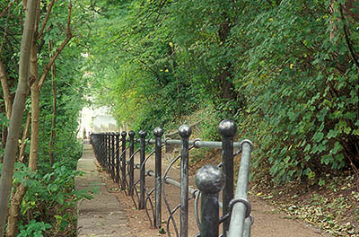 ENG: Northumbria Region, Durham, Durham Borough, Medieval Durham, A paved path with an elaborate iron railing climbs through forests from the River Wear [Ask for #262.357.]