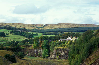 ENG: Northumbria Region, Durham, Stanhope, Houses crowd against the high wall of an abandoned quarry, with views over the Pennines [Ask for #262.392.]