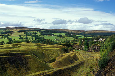 ENG: Northumbria Region, Durham, Stanhope, Houses crowd against the high wall of an abandoned quarry, with views over the Pennines [Ask for #262.394.]