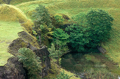 ENG: Northumbria Region, Durham, Stanhope, A pond has formed in the lowest part of an abandoned strip mine, ringed by high stone cliffs [Ask for #262.399.]