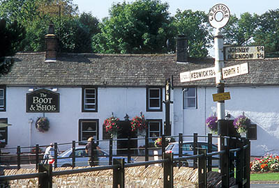 ENG: The Northwest Region, Cumbria, The Eden Valley, Penrith, Greystoke Village, View across village green to the local pub, the Boot and Shoe; traditional cast iron signpost gives village name, points to Keswick and Penrith [Ask for #262.447.]