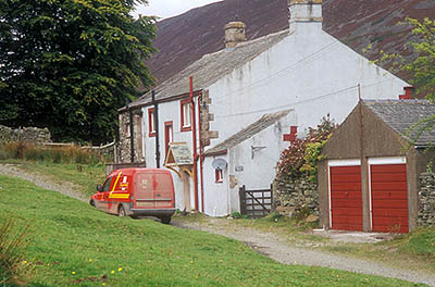 ENG: The Northwest Region, Cumbria, Lake District National Park, Skiddaw Fells, Mungrisdale, Blencathra Area, A Royal Mail truck makes a delivery at a delapidated row house at the end of a rough village lane. [Ask for #262.458.]