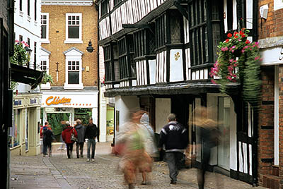 ENG: West Midlands Region, Shropshire, Shrewsbury and Atcham District, Shrewsbury, Historic half-timbered buildings overhang Butchers Row, a pedestrianized downtown street [Ask for #262.534.]