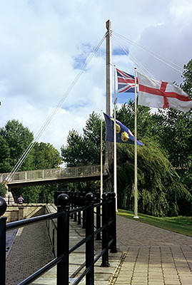 ENG: West Midlands Region, Shropshire, Shrewsbury and Atcham District, Shrewsbury, The Union Jack and St. Georges flag fly above a paved foot path along the River Severn, by the cable-stayed Framwell Bridge [Ask for #262.540.]