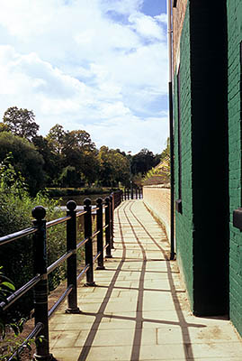 ENG: West Midlands Region, Shropshire, Shrewsbury and Atcham District, Shrewsbury, A door from a green building lets out on a paved foot path, with iron rails, along the River Severn at Welsh Bridge [Ask for #262.545.]