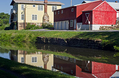 MD: Washington County, Potomac River Gorge, Hancock, Chesapeake and Ohio Canal National Historic Park, Town center buildings reflected in the canal's waters [Ask for #269.048.]