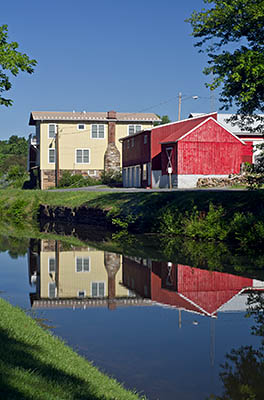 MD: Washington County, Potomac River Gorge, Hancock, Chesapeake and Ohio Canal National Historic Park, Town center buildings reflected in the canal's waters [Ask for #269.049.]