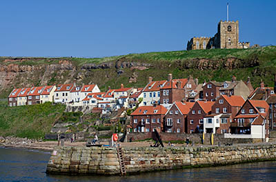 ENG: Yorkshire & Humberside Region, North Yorkshire, North Yorkshire Coast, Whitby, West Pier, Houses bunch beneath cliffs at the mouth of the harbor [Ask for #270.161.]