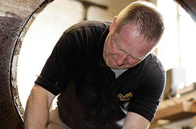 ENG: West Midlands Region, Staffordshire, The Trent Valley, Burton-on-Trent, Marstons Brewery, Shobnall, Mark Newton, Marston's cooper, scrapes the inside of a barrel. [Ask for #270.228.]