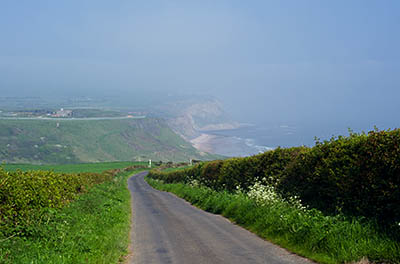 ENG: Yorkshire & Humberside Region, North Yorkshire, North Yorkshire Coast, Skinningrove, Narrow cliff-top lane heads down into gorge that cuts sea cliffs, into which this iron-mining town is tucked [Ask for #270.456.]