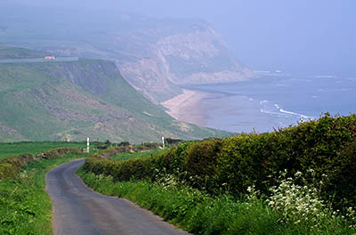 ENG: Yorkshire & Humberside Region, North Yorkshire, North Yorkshire Coast, Skinningrove, Narrow cliff-top lane heads down into gorge that cuts sea cliffs, into which this iron-mining town is tucked [Ask for #270.457.]