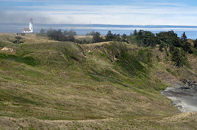 OR: South Coast Region, Curry County, North Coast, Cape Blanco Area, Cape Blanco State Park, View of the Cape Blanco Lighthouse atop grassy cliffs as fog rolls in. [Ask for #274.667.]