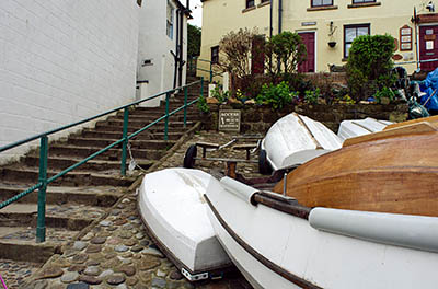 ENG: Yorkshire & Humberside Region, North Yorkshire, North Yorkshire Coast, Sea Cliffs, Robin Hood's Bay, Stone cottages, perched on cliff terrace, front on stone-paved foot-only lane; boats pulled up from town harbor [Ask for #270.080.]